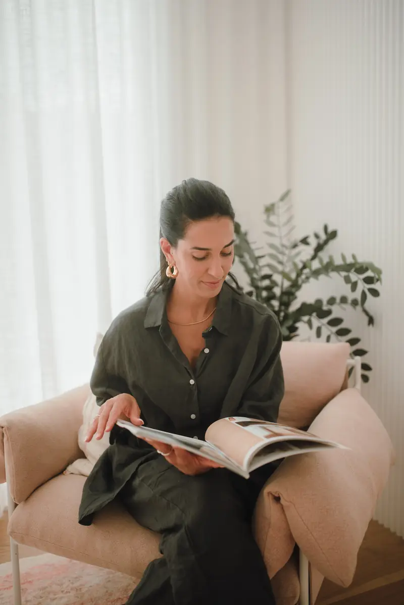 Ive Bitencourt reading in a calm, clutter-free lounge room